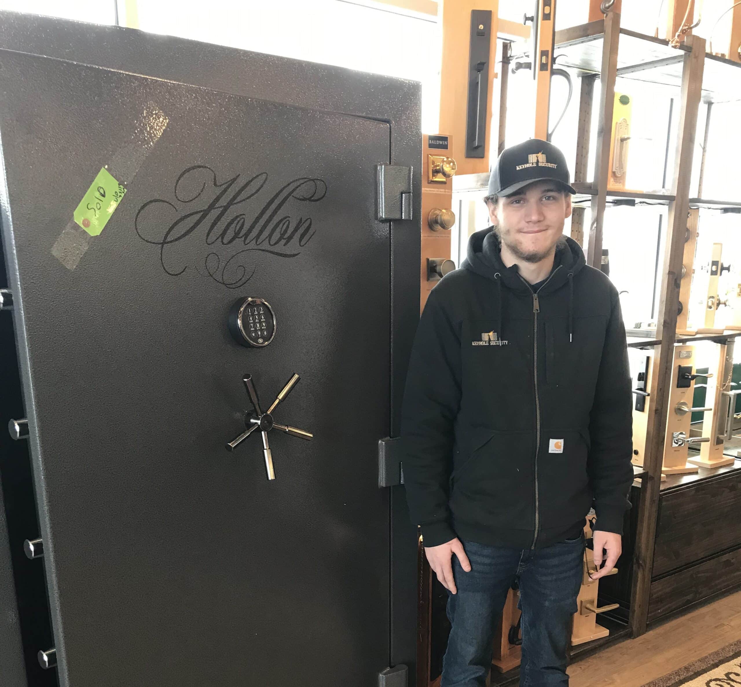 Skyler Miller stands next to a large safe at Keyhole Security in Wenatchee, WA.