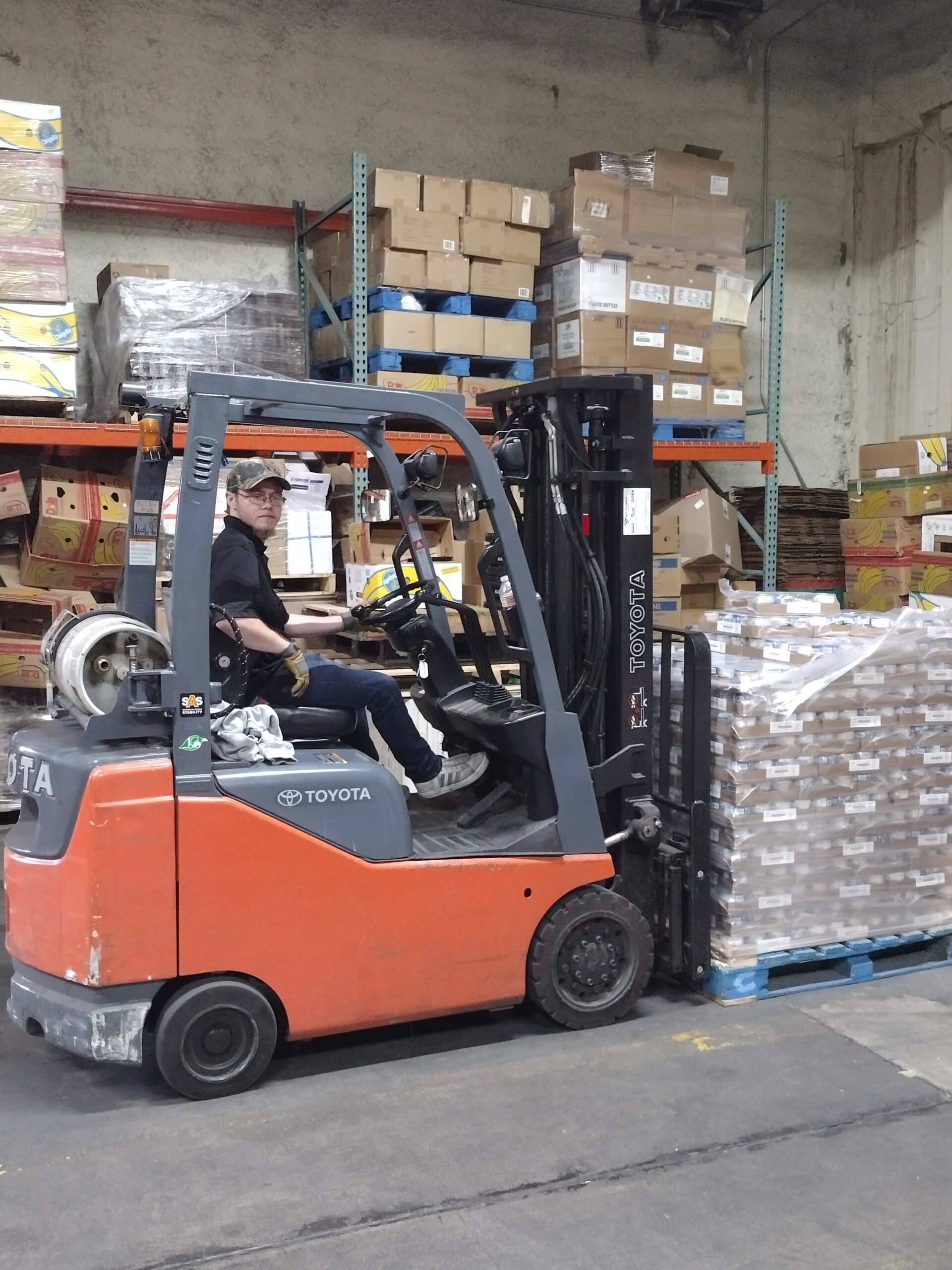 A man drives a forklift in a food distribution center warehouse..