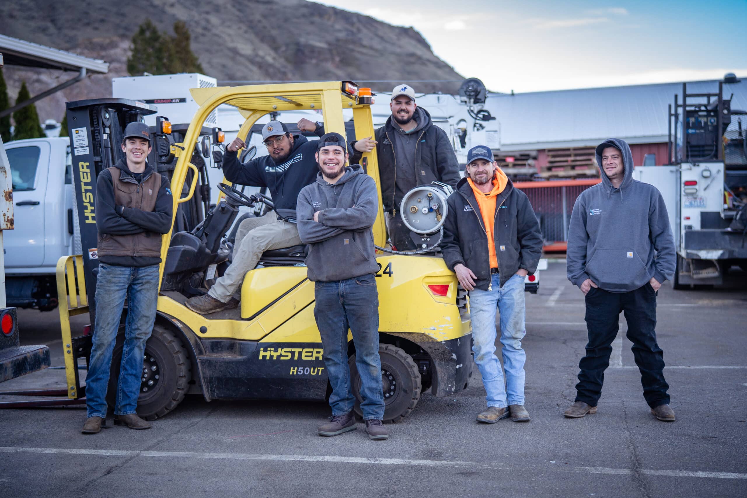 Several irrigation technicians pose on a yellow forklift after receiving their certification through incumbent worker training.