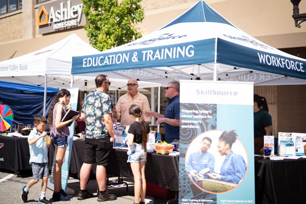 A family of four are at a booth about Education &amp; training getting information
