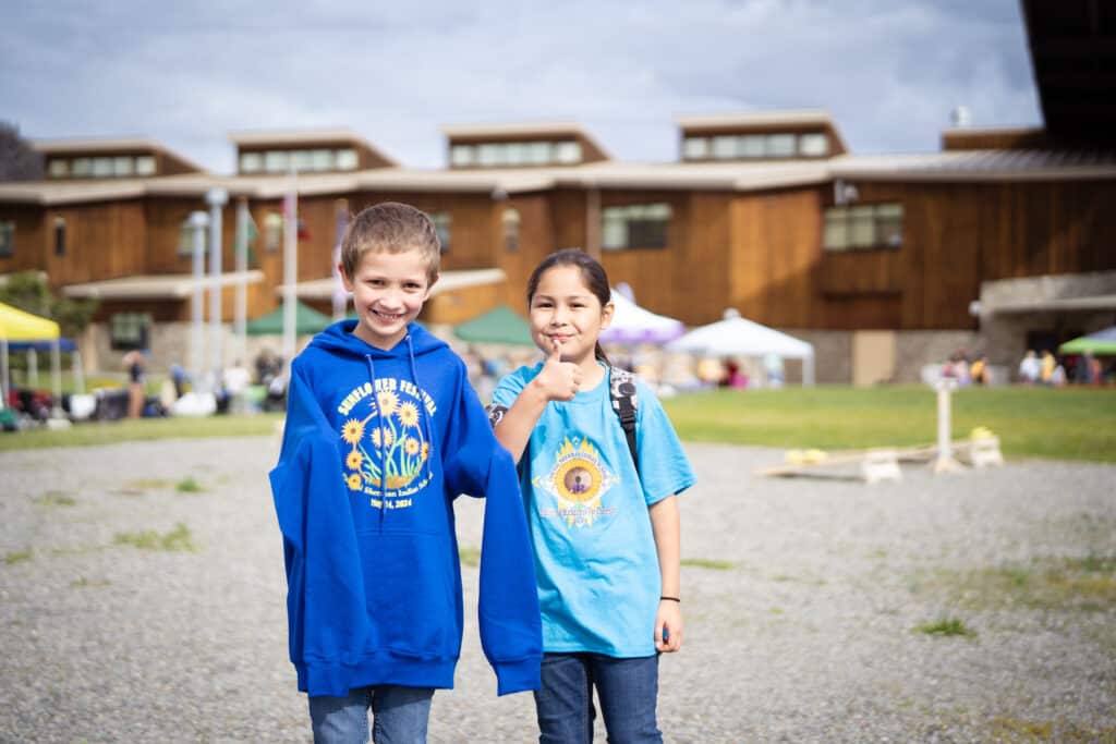 Two kids wearing blue tops smiling at the camera