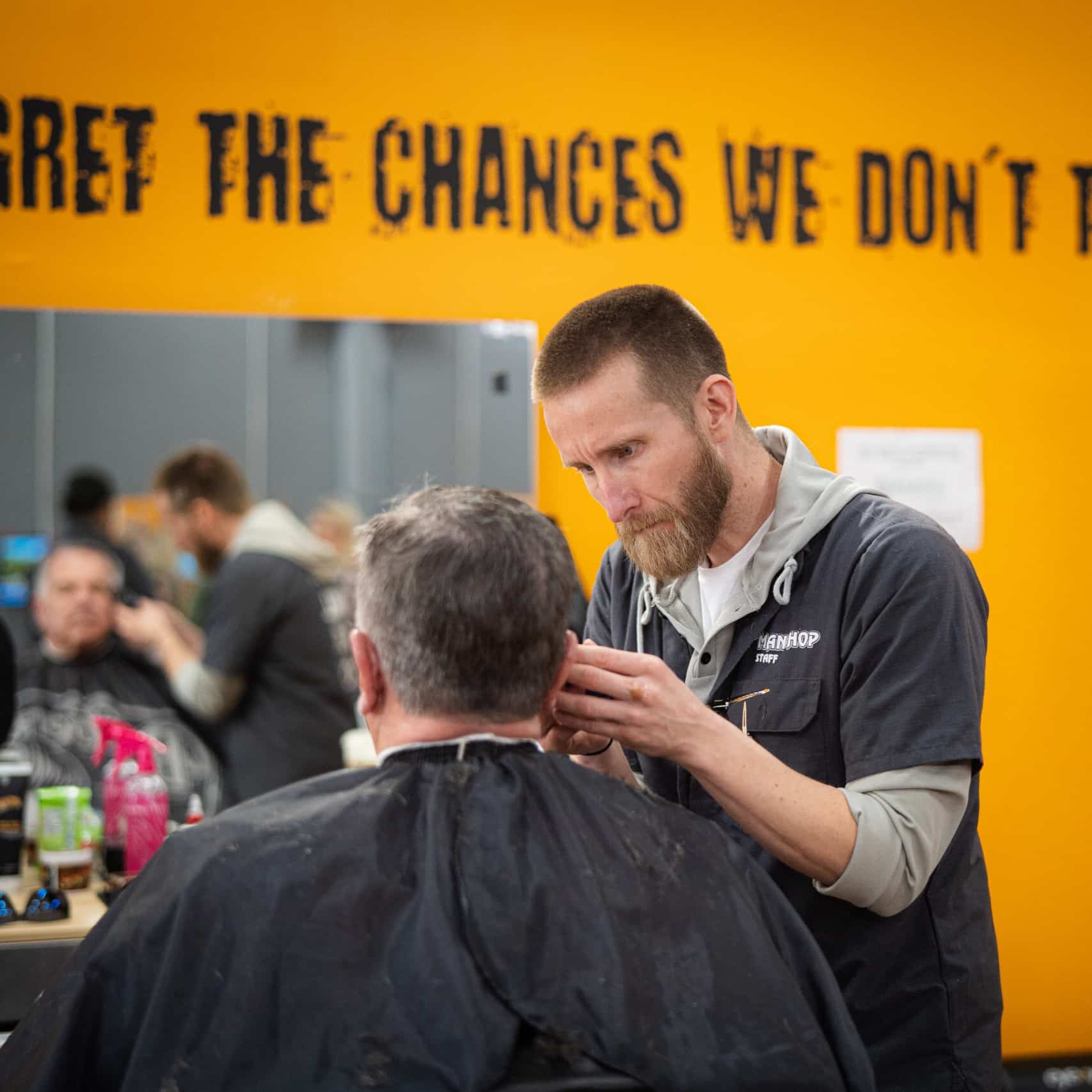 A barber apprentice learns the trade on the job.